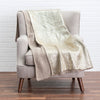 Knitted blanket draped over a chair with a white brick wall background
