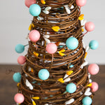 Brown mini Easter cone trees decorated with pastel eggs and yellow berries.