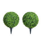 Two artificial topiary balls on stands against a white background
