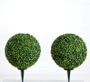 Two artificial boxwood balls on stands against a white background