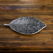Metal leaf-shaped object on a wooden surface