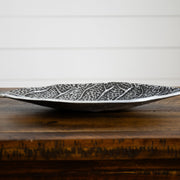Decorative silver leaf-patterned bowl on a wooden surface with a white background