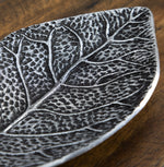 Decorative plate with leaf pattern on a wooden surface