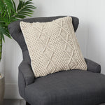 Textured beige pillow on a gray armchair with a plant in the background