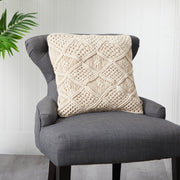 Gray chair with a textured beige pillow against a white paneled wall.