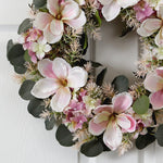 Floral wreath with pink and white flowers on a white door