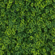 A dense, textured green artificial hedge or living wall panel made of many small leafy branches and foliage pieces, filling the entire frame.