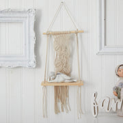 Wall-mounted macrame shelf with decorative items against a white paneled wall.