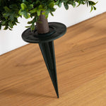 Black plant support stake holding a potted plant on a wooden floor.