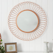 Decorative round mirror with a gold wire frame on a white wall.