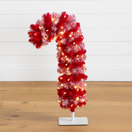 A red and white flocked candy cane Christmas tree with warm white string lights, displayed on a white stand on a wooden floor against a white paneled wall.