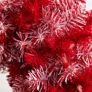 Close-up of a red artificial Christmas tree with white-tipped needles and small red lights.