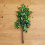 Artificial green leaf branch on a wooden surface
