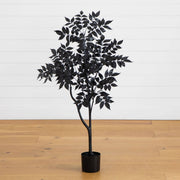 Black artificial tree in a pot on a wooden floor with a white paneled wall background