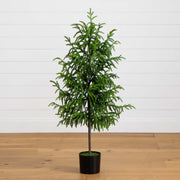 Potted artificial Christmas tree on a wooden floor with a white wall background