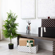 Decorative scene with wrapped gifts, a plant, and a reindeer figurine on a table.