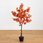 Potted artificial tree with orange leaves on a wooden floor and white wall background