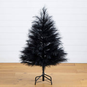 Black artificial Christmas tree on a wooden floor with a white wall background