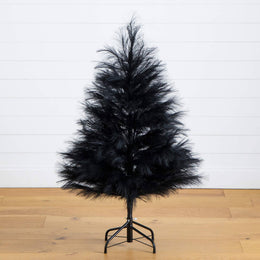 Black artificial Christmas tree on a wooden floor with a white wall background