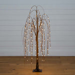 Decorative tree with lights against a plain wall