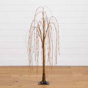 Artificial willow tree with a metallic finish on a wooden floor against a white wall.