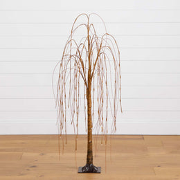 Artificial willow tree with a metallic finish on a wooden floor against a white wall.