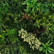 A dense, top-down view of a lush artificial green wall made of various artificial plants, ferns, and leafy vines in shades of green with some reddish accents.
