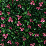 A dense artificial foliage wall featuring glossy dark green leaves and clusters of pink bougainvillea-style flowers, filling the entire frame.