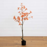 Potted artificial tree with orange leaves on a wooden floor against a white wall