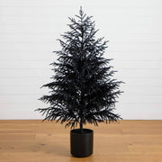 Black artificial Christmas tree in a pot on a wooden floor with a white wall background