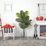 Living room with a white armchair, decorative pillows, a large green plant, and a fireplace.