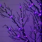 Purple LED branch lights strung along bare black decorative branches against a purple-lit background.