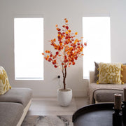 Decorative indoor tree with autumn leaves in a living room setting.