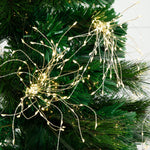Warm white LED tree lights draped across the branches of a green artificial Christmas tree, casting a soft glow.