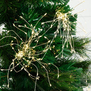 Warm white LED tree lights draped across the branches of a green artificial Christmas tree, casting a soft glow.