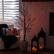 Decorative indoor scene with a small tree, ghost pillow, and candlelit lanterns.