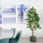 Modern interior with abstract art, a plant, and a table with chairs.