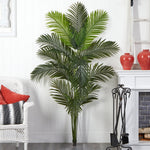 Artificial palm plant in a living room setting with a white wall and fireplace.