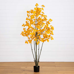 Artificial yellow leaf tree in a pot on a wooden floor with a white wall background
