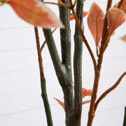 Artificial plant with orange leaves and dark branches against a white background