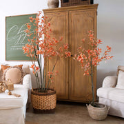 Living room with wooden cabinet, floral arrangements, and decorative items.