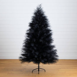 Black artificial Christmas tree on a wooden floor with a white wall background