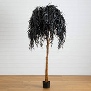 Artificial potted tree with dark foliage on a wooden floor and white wall background