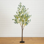 An artificial eucalyptus tree with green leaves and warm white string lights, standing on a black base against a white shiplap wall and light wood floor.