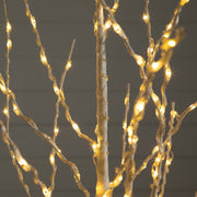 Warm white LED branch lights wrapped around a white decorative tree trunk, with glowing lights on twisting wire branches against a dark gray background.