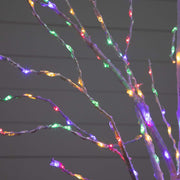 Multicolor LED fairy lights wrapped on thin decorative branches, glowing against a dark gray paneled background.