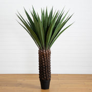 Tall artificial plant with decorative pot on a wooden floor against a white wall