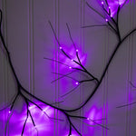 Decorative branch with purple LED lights against a white paneled wall