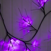 Decorative branch with purple LED lights against a white paneled wall