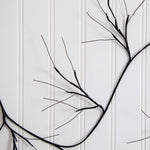 Black branch wall decor with multiple thin branches and small metallic bead accents, mounted against a white paneled wall.